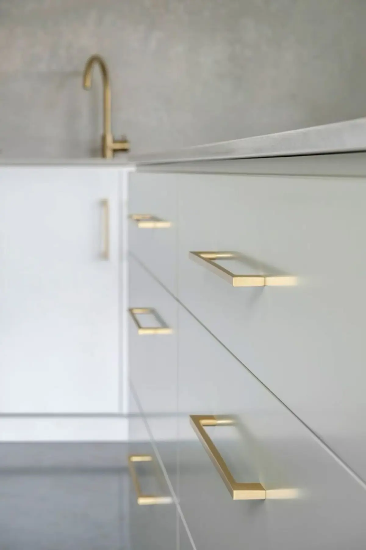 دستگیره طلایی و برنجی نصب شده روی کابینت های گلاس سفید