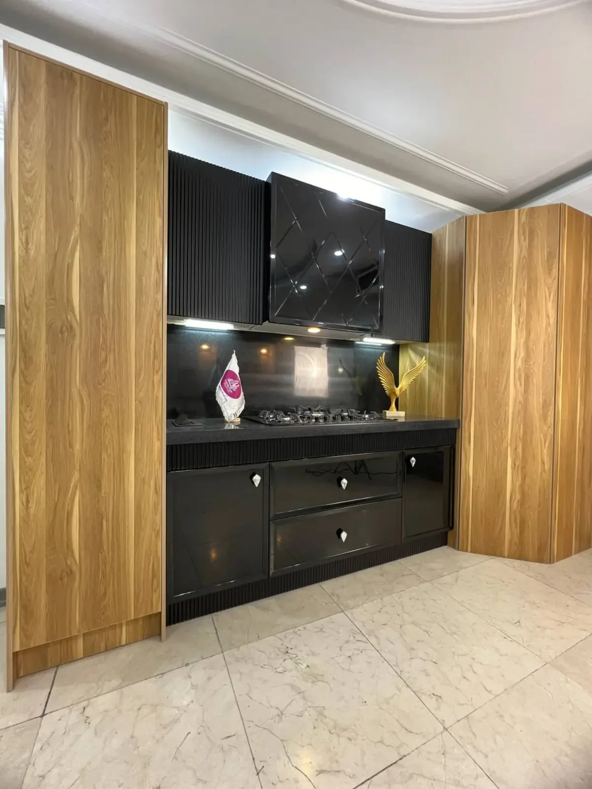 کابینت انزو مشکی ترکیب با طرح چوب و هود مشکی توکار و دستگیره های نقره ای