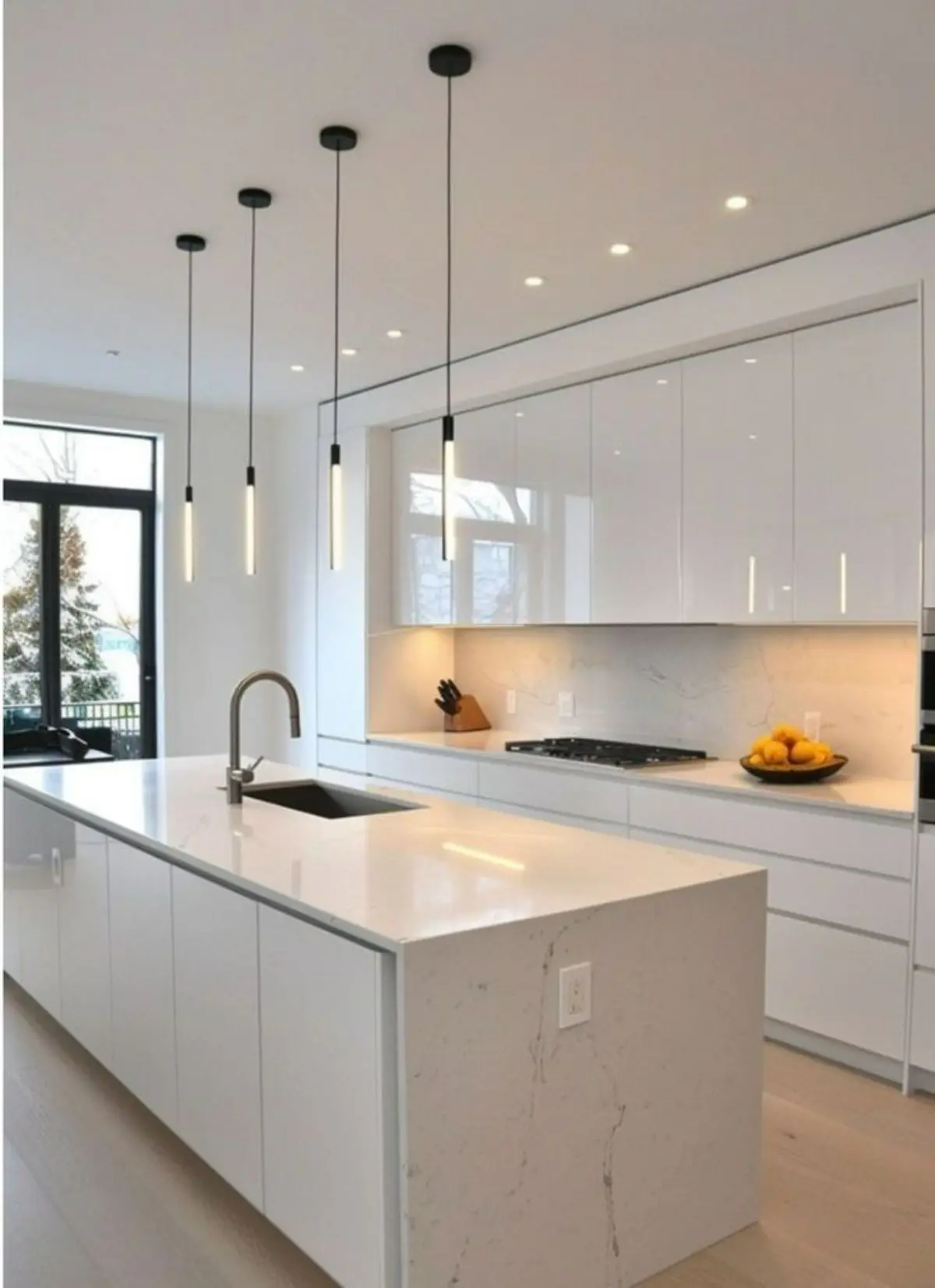 کابینت و جزیره هایگلاس سفید بدون دستگیره با چراغ‌های آویز مشکی بالای جزیره